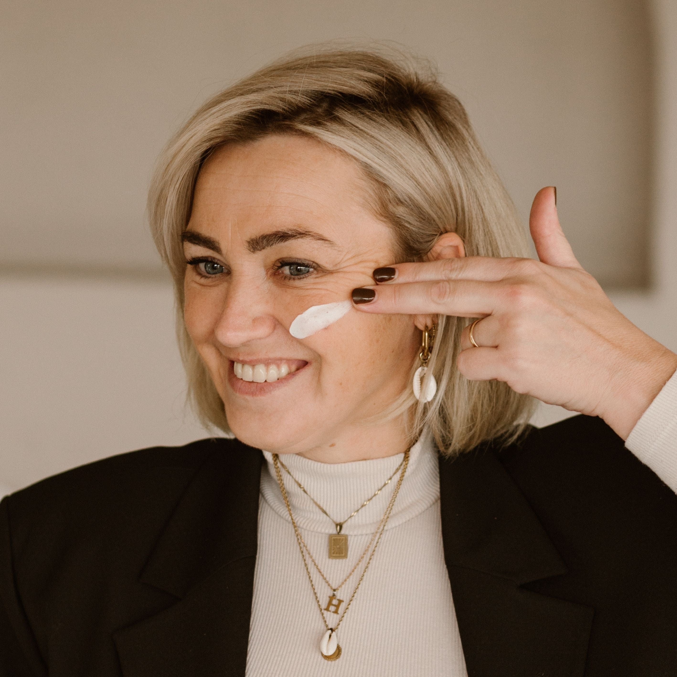 Vrouw met blond haar die creme op haar gezicht smeert
