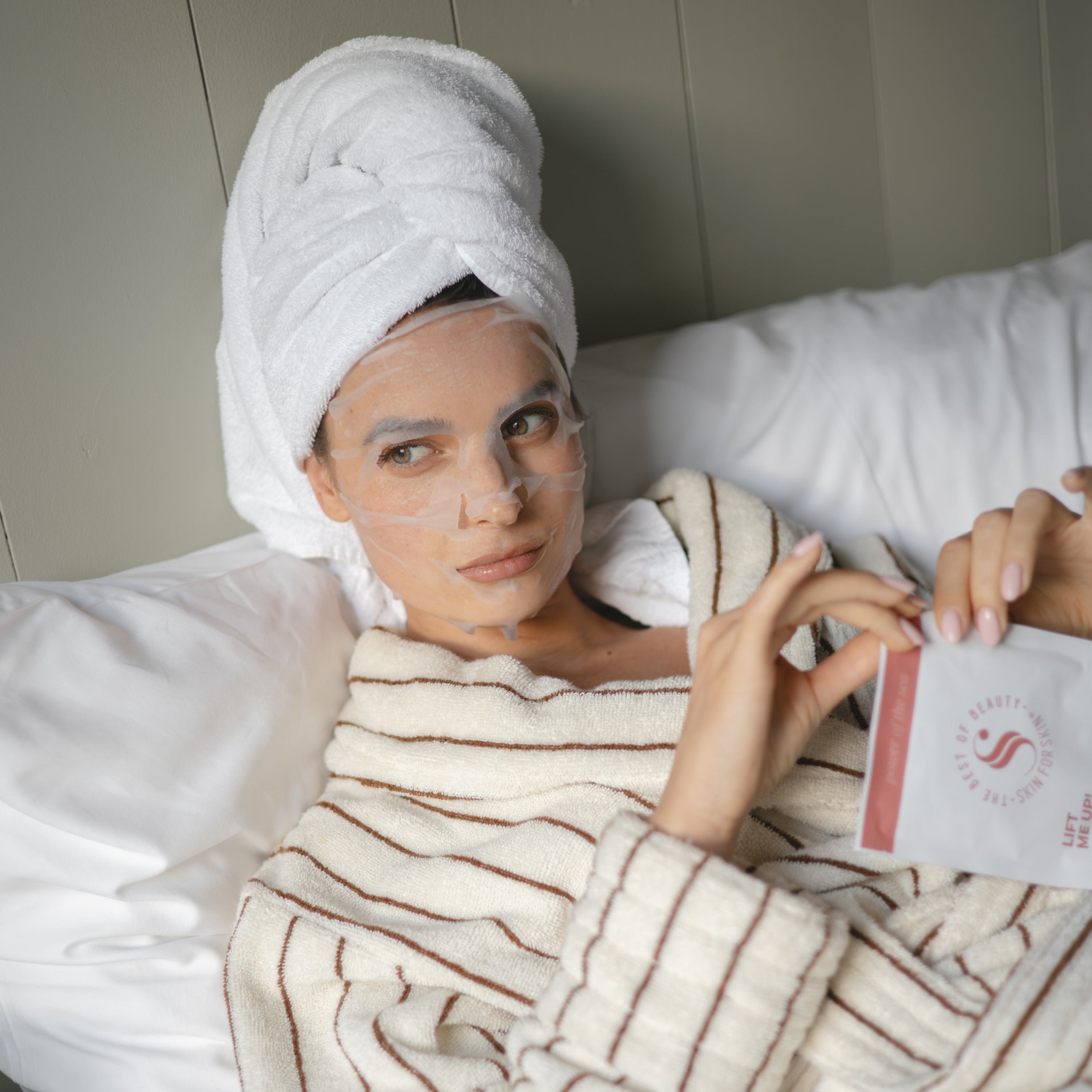een vrouw liggend op bed met een beautymasker op haar gezicht
