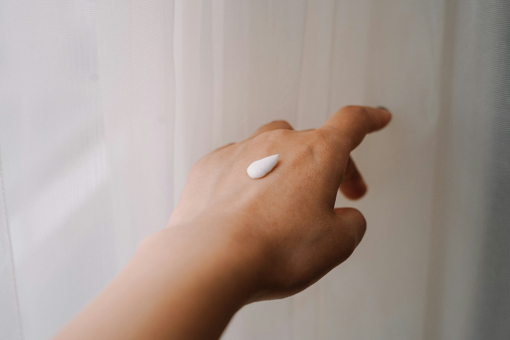 Hand met een kleine hoeveelheid crème op de huid.