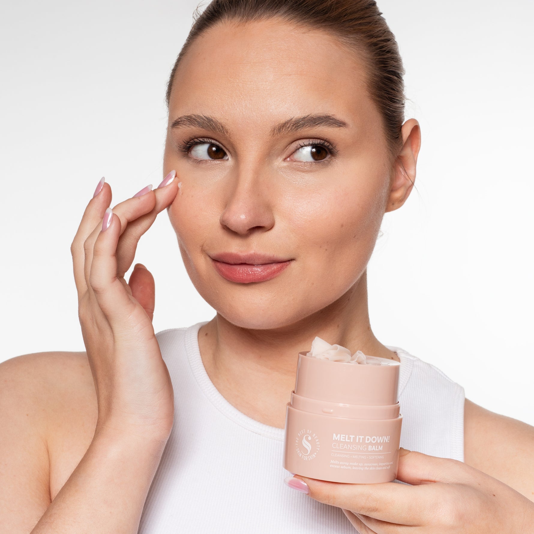 Vrouw brengt Skin for Skin Melt It Down cleansing balm aan en houdt het potje vast.