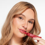 Vrouw brengt Skin for Skin My Lips Are Sealed balmy lip gloss in Blushed aan voor een frisse, glanzende liplook.