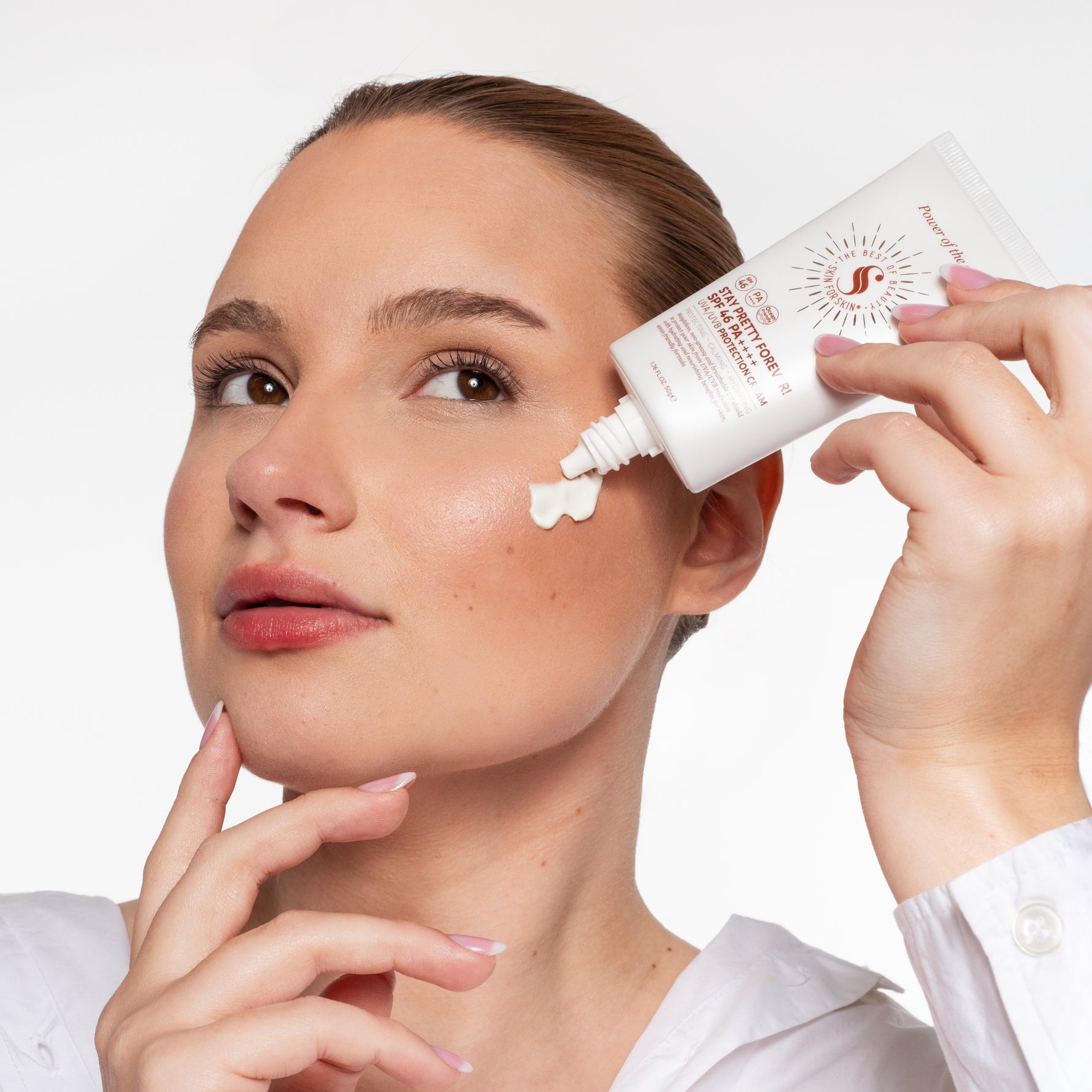 Vrouw brengt Skin for Skin SPF face cream aan op haar wang voor dagelijkse bescherming.