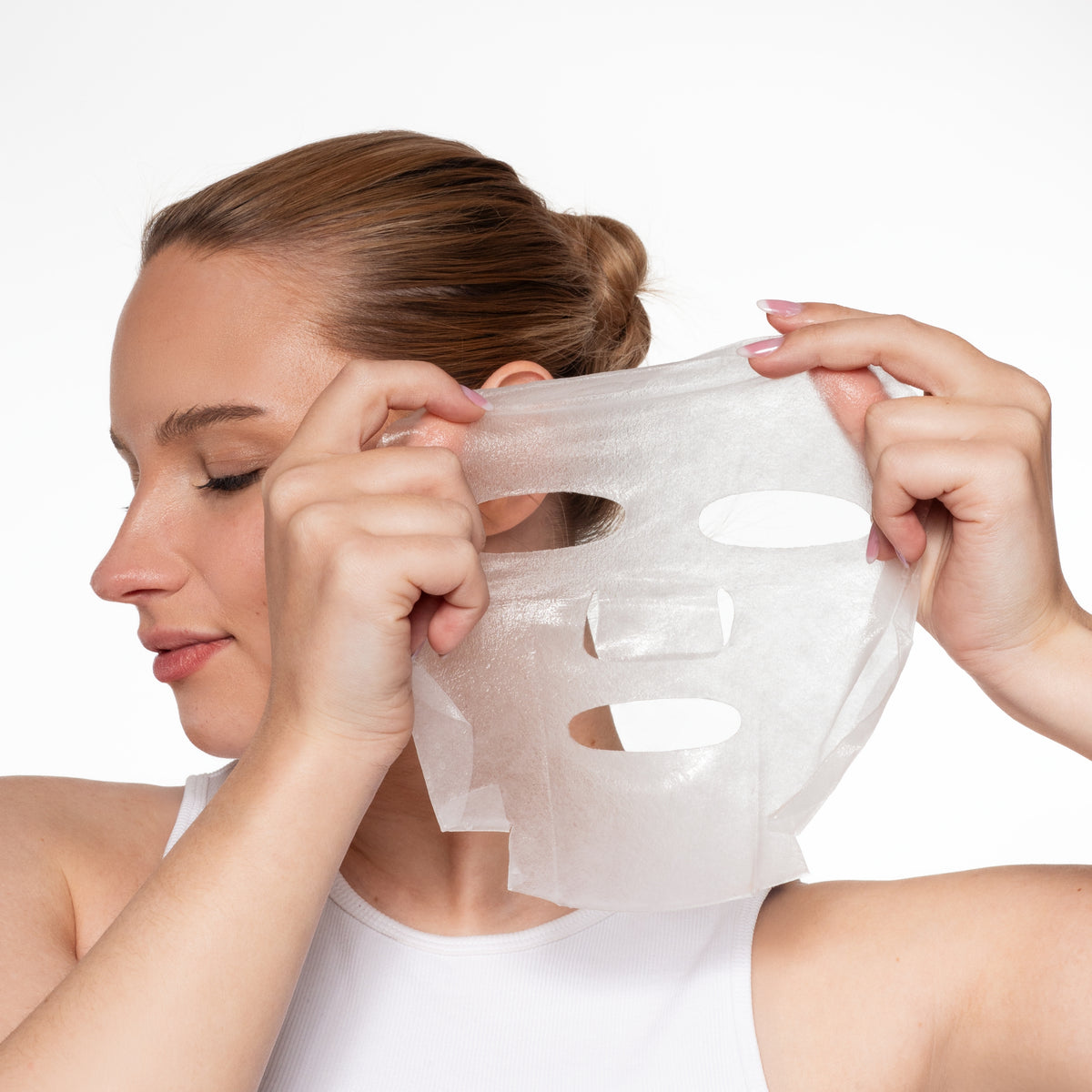 Vrouw houdt Skin for Skin Instant Glow sheetmasker voor haar gezicht en bereidt zich voor op gebruik.