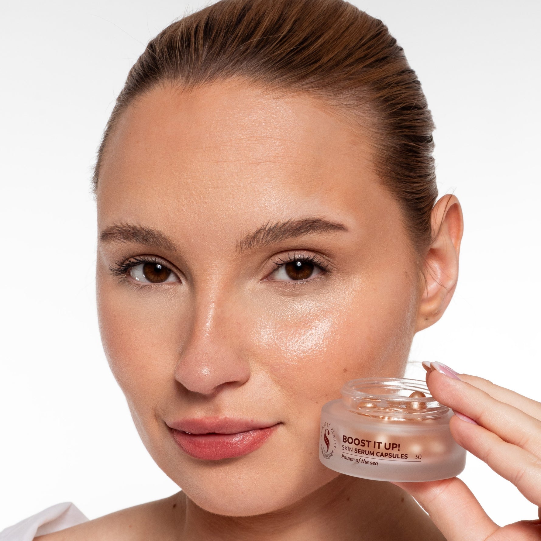 Vrouw toont Skin for Skin Boost It Up serum capsules met een stralende huid.
