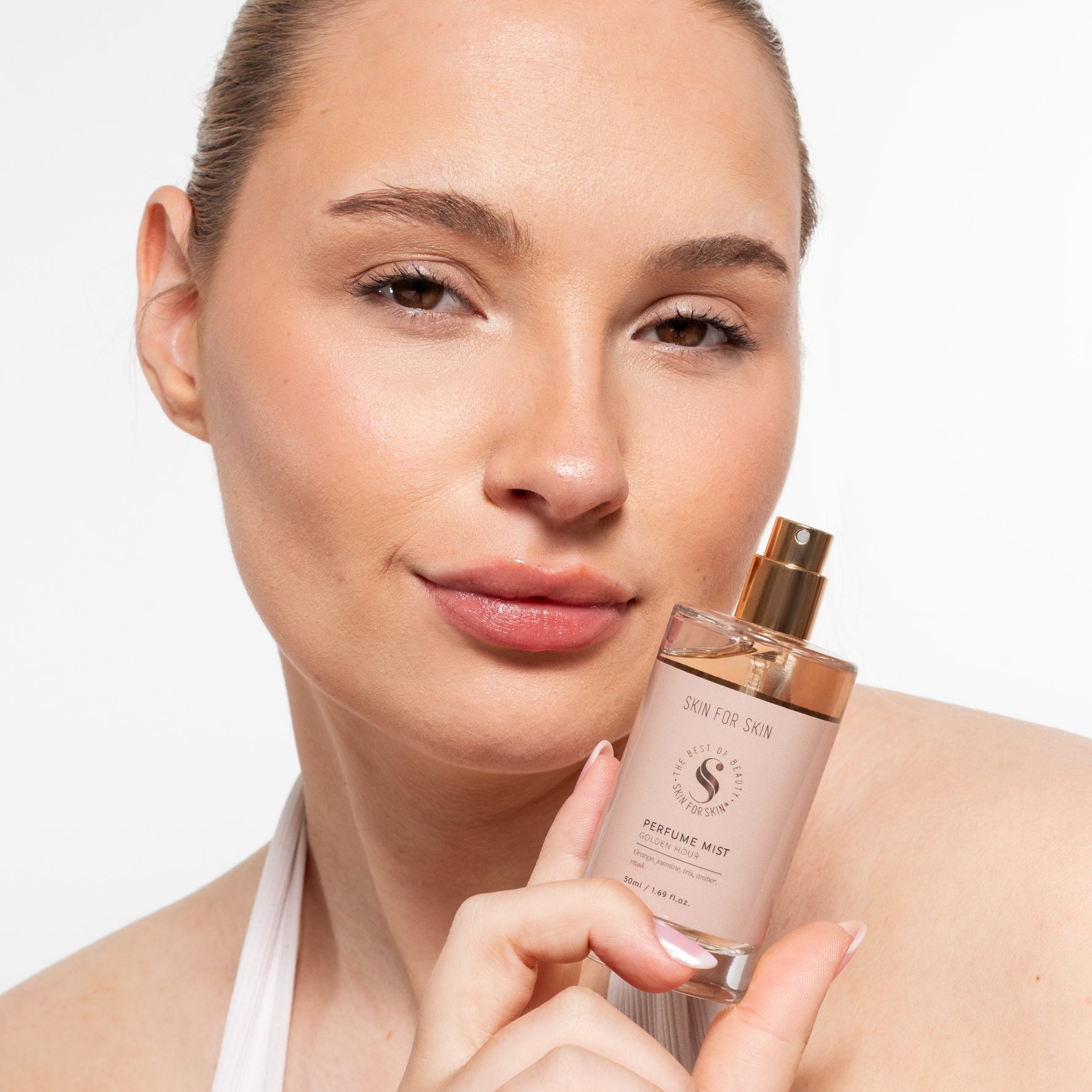 Vrouw toont Skin for Skin Perfume Mist Golden Hour voor een frisse, subtiele geur.